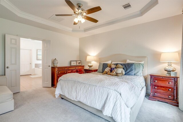 bedroom with crown molding, visible vents, light colored carpet, connected bathroom, and a tray ceiling