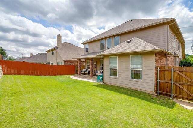 rear view of house featuring a patio, a fenced backyard, and a lawn