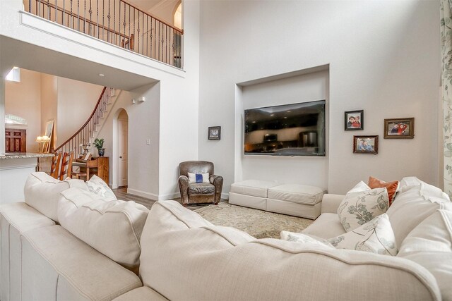 living room with wood finished floors, baseboards, a high ceiling, stairway, and arched walkways