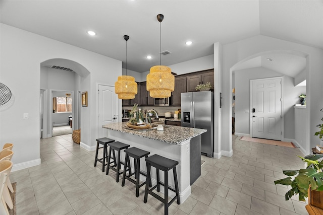 kitchen featuring arched walkways, stainless steel appliances, a kitchen bar, and visible vents