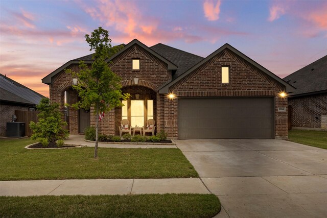 view of front of home with a garage, brick siding, central AC, a front lawn, and concrete driveway
