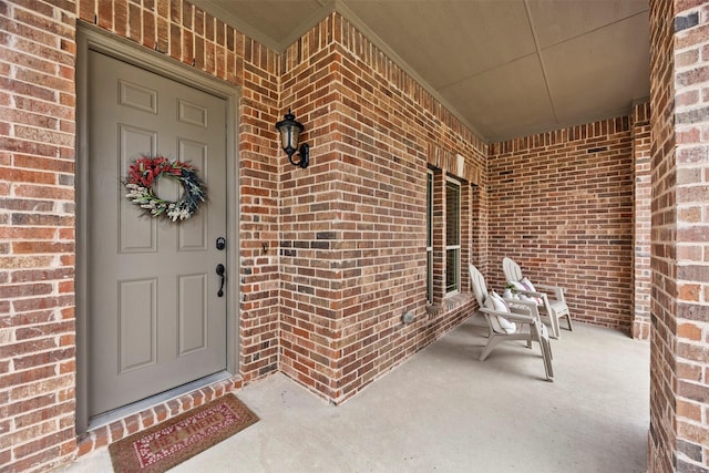 property entrance with covered porch and brick siding