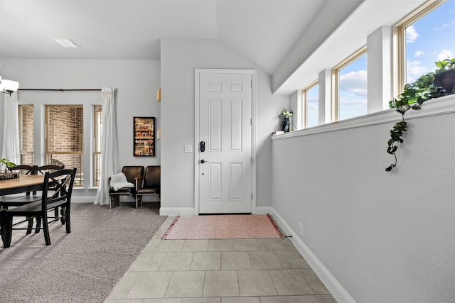 foyer entrance with tile patterned flooring, baseboards, lofted ceiling, and visible vents