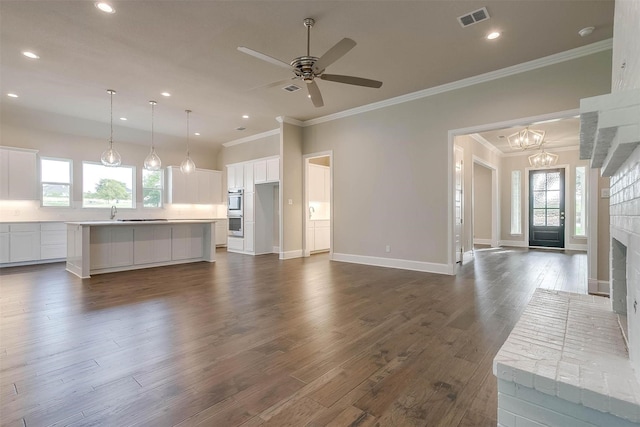 unfurnished living room with visible vents, plenty of natural light, and crown molding