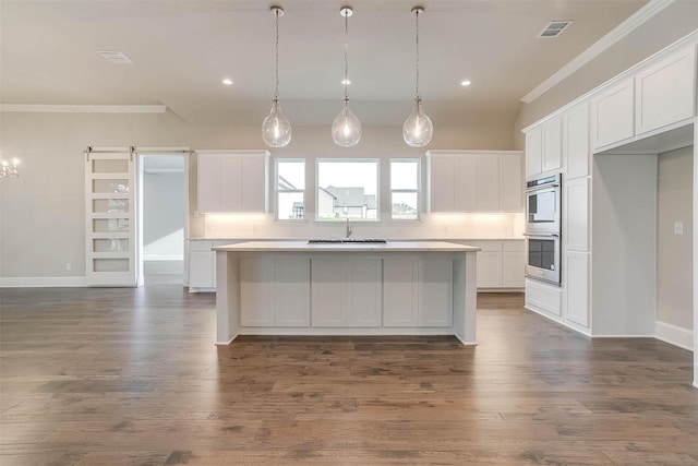 kitchen with visible vents, ornamental molding, a center island, stainless steel double oven, and white cabinets
