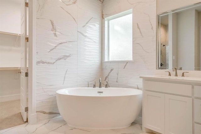 full bath featuring a healthy amount of sunlight, vanity, a freestanding tub, and marble finish floor