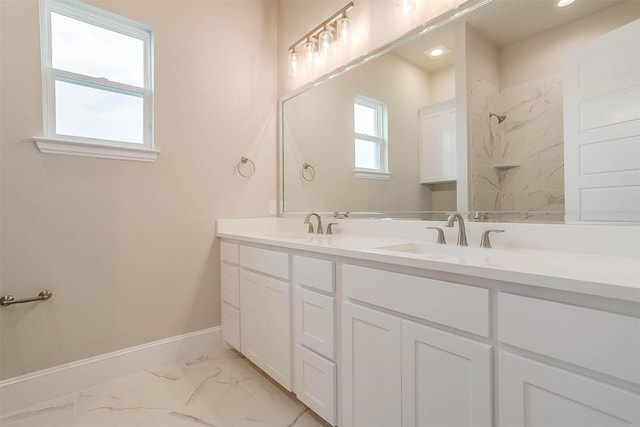 bathroom featuring walk in shower, a sink, double vanity, marble finish floor, and baseboards