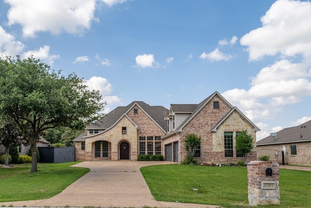 french provincial home with brick siding, a garage, fence, and driveway