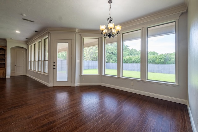 unfurnished dining area with arched walkways, a chandelier, dark wood finished floors, baseboards, and visible vents