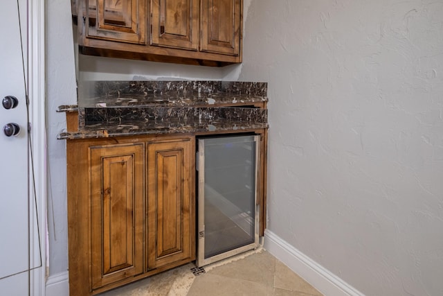 bar with beverage cooler, a dry bar, baseboards, and light tile patterned floors