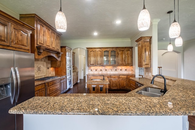 kitchen with brown cabinets, stainless steel appliances, arched walkways, and a sink