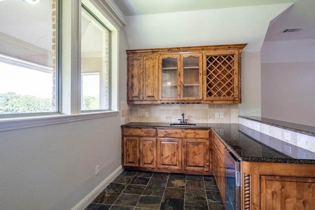 bar with visible vents, decorative backsplash, baseboards, indoor wet bar, and a sink