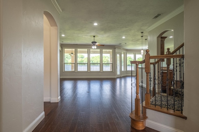 unfurnished living room with baseboards, arched walkways, ceiling fan, and wood finished floors