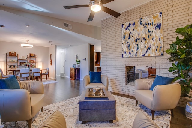 living area featuring brick wall, a ceiling fan, baseboards, wood finished floors, and visible vents