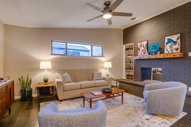 living area with built in features, a brick fireplace, wood finished floors, baseboards, and a ceiling fan