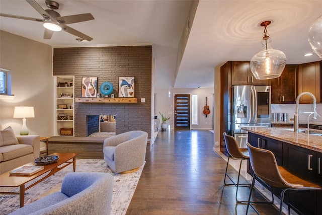living area featuring a ceiling fan, dark wood finished floors, and a fireplace