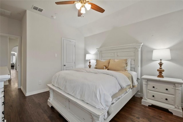 bedroom featuring dark wood-style flooring, arched walkways, baseboards, and visible vents