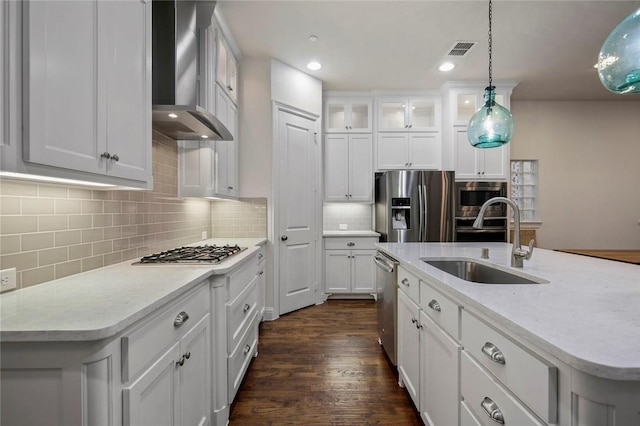 kitchen featuring a sink, wall chimney exhaust hood, stainless steel appliances, decorative light fixtures, and visible vents