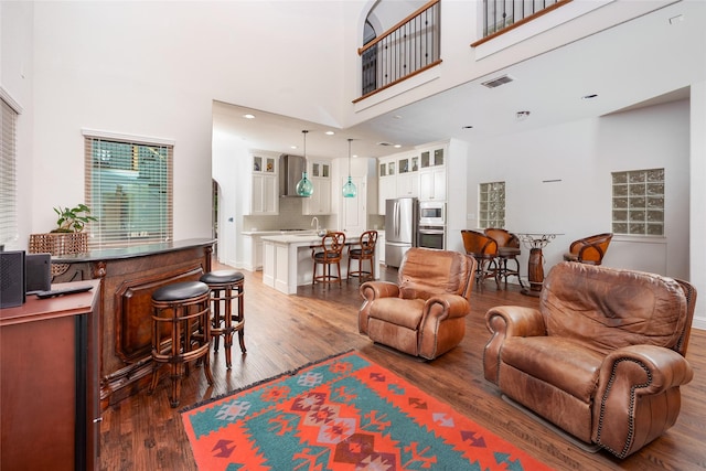 living room with a high ceiling, wood finished floors, and visible vents