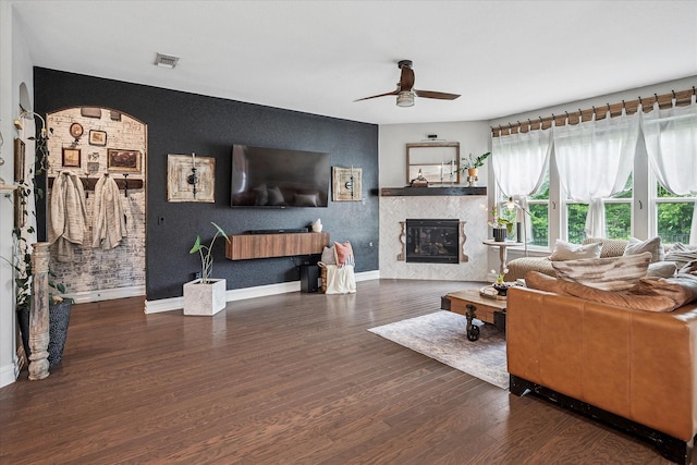 living room with baseboards, ceiling fan, wood finished floors, and a tile fireplace