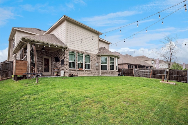 back of house with a fenced backyard, ceiling fan, a lawn, and brick siding