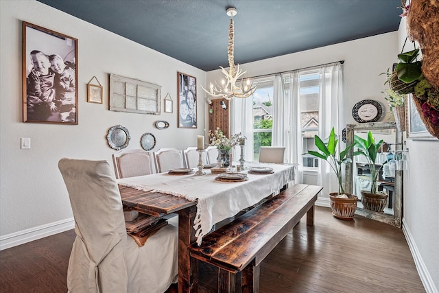 dining space with an inviting chandelier, baseboards, and wood finished floors