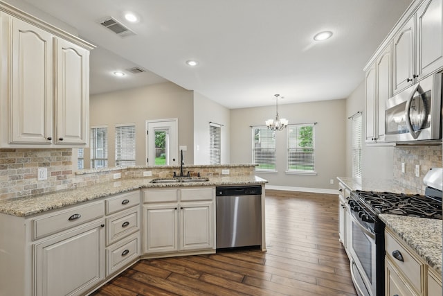 311 Wilson St, Whitesboro, TX 76273 - kitchen with a sink, a peninsula, a chandelier, decorative backsplash, and stainless steel appliances