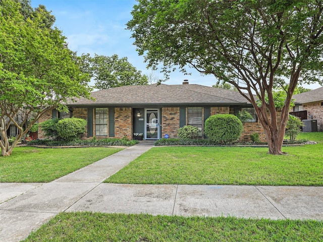 ranch-style home with brick siding, a chimney, central AC, and a front yard
