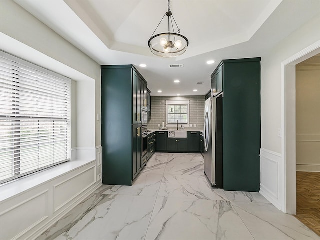 kitchen with a sink, a wainscoted wall, green cabinetry, and stainless steel appliances