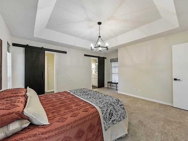 carpeted bedroom with baseboards, a barn door, a raised ceiling, and an inviting chandelier