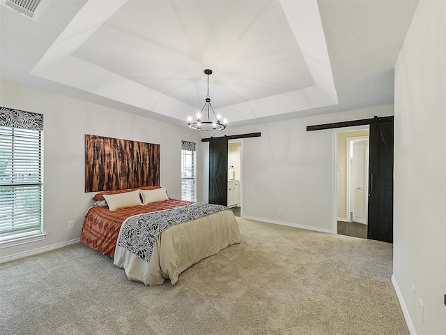 bedroom with a tray ceiling, carpet flooring, a barn door, and visible vents