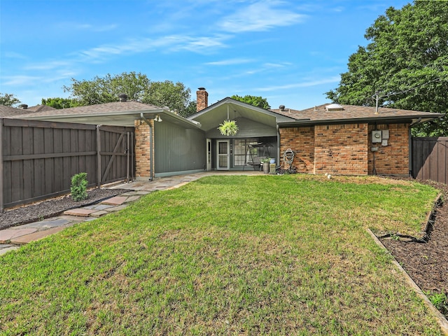 back of property featuring a shingled roof, brick siding, a fenced backyard, a chimney, and a lawn