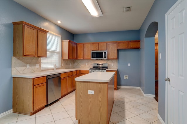 kitchen with visible vents, appliances with stainless steel finishes, tasteful backsplash, arched walkways, and light countertops