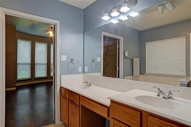 bathroom featuring double vanity, a sink, a ceiling fan, and wood finished floors