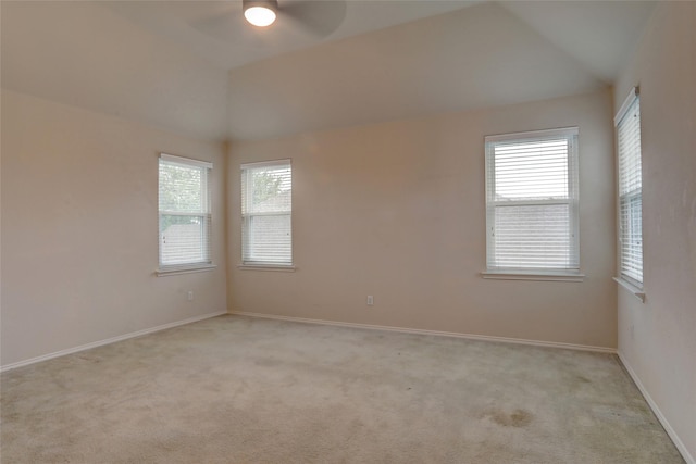 empty room with ceiling fan, vaulted ceiling, and light carpet