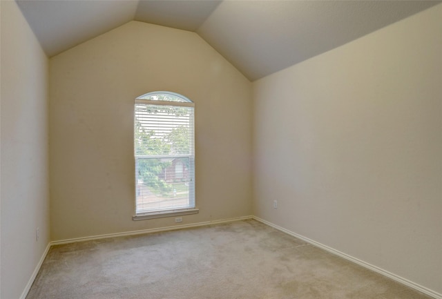 spare room with baseboards, light colored carpet, plenty of natural light, and vaulted ceiling