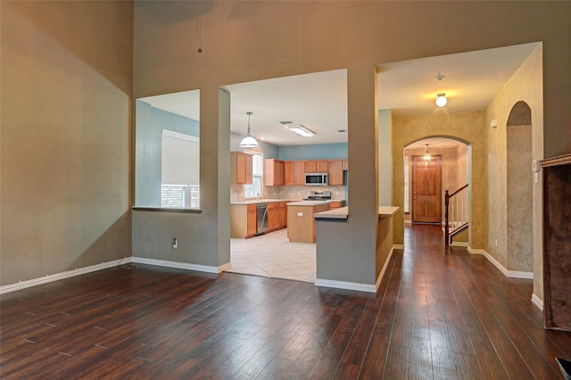 kitchen with appliances with stainless steel finishes, arched walkways, light countertops, baseboards, and hardwood / wood-style floors