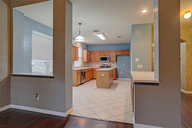 kitchen with baseboards, light wood-type flooring, light countertops, backsplash, and stainless steel appliances