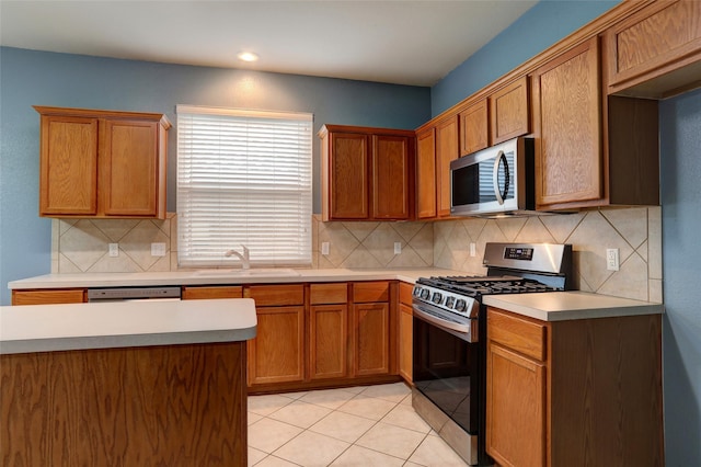 kitchen featuring a sink, light countertops, decorative backsplash, and stainless steel appliances