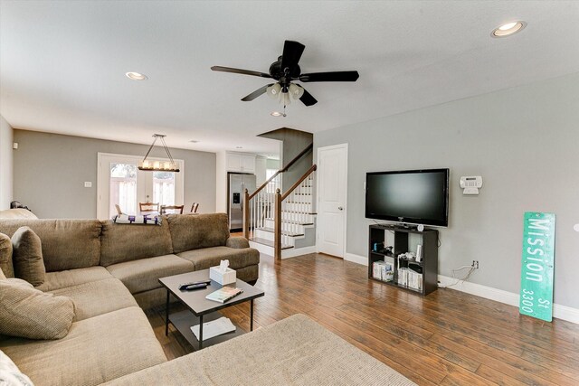 living area with stairs, baseboards, ceiling fan with notable chandelier, recessed lighting, and dark wood-type flooring