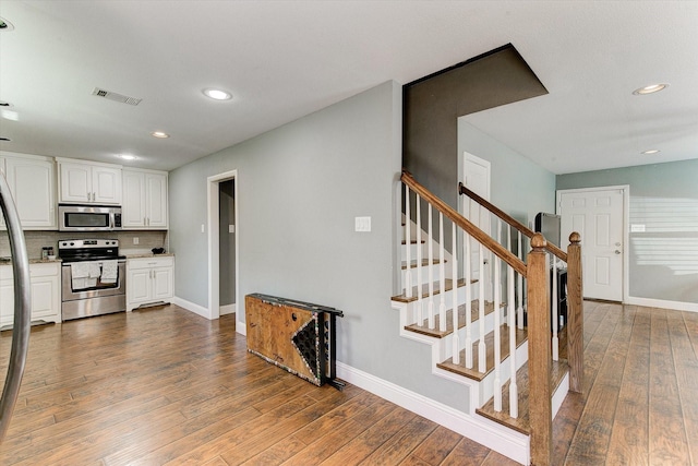 kitchen with visible vents, hardwood / wood-style flooring, baseboards, stainless steel appliances, and white cabinetry