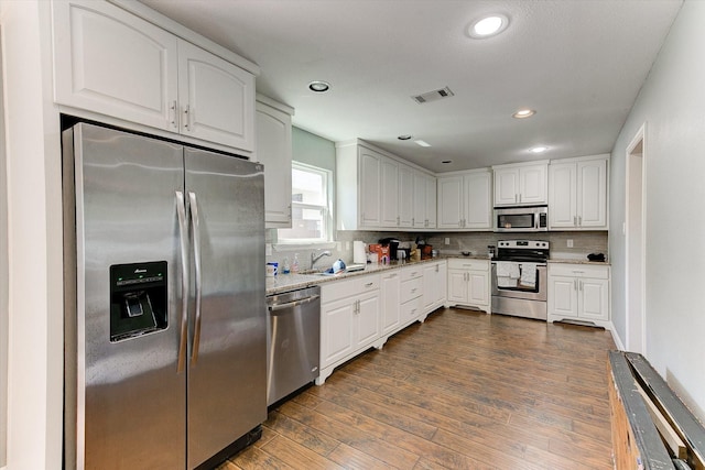 kitchen with backsplash, visible vents, a sink, stainless steel appliances, and dark wood-type flooring
