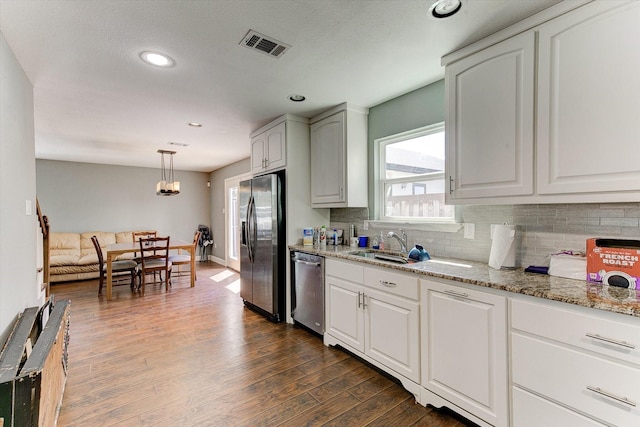 kitchen featuring visible vents, appliances with stainless steel finishes, tasteful backsplash, light stone countertops, and a sink