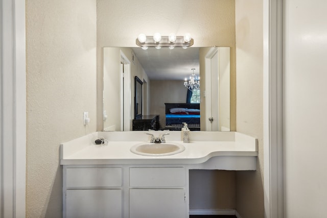 ensuite bathroom with vanity, a textured wall, ensuite bathroom, and an inviting chandelier