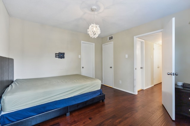 bedroom with baseboards, a notable chandelier, wood finished floors, and visible vents