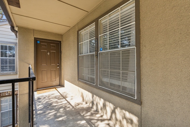 entrance to property featuring covered porch and stucco siding
