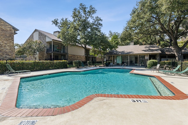 community pool with fence and a patio area