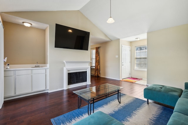 living area featuring baseboards, a fireplace, vaulted ceiling, and wood finished floors