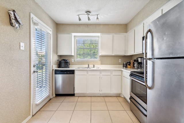 kitchen with light countertops, white cabinets, appliances with stainless steel finishes, and a sink