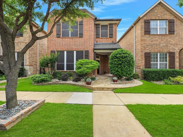 traditional home with brick siding and a front lawn